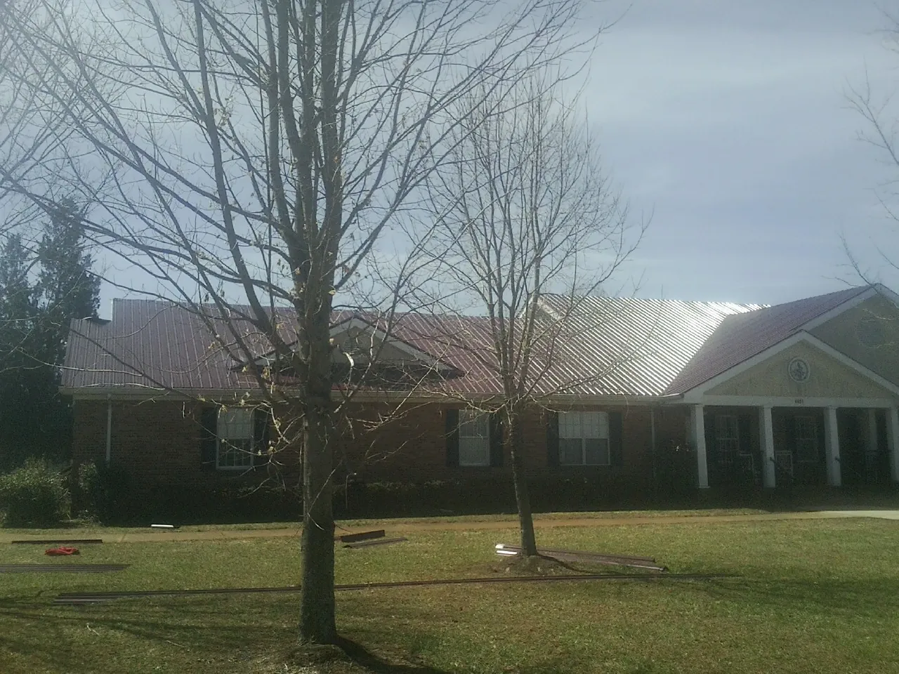 Red metal roof on a brick building seen from the front lawn in Essex