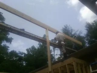 Carpenter setting a ridge beam over a new addition frame — Ice Dam Removal by Roofing Brothers in Essex