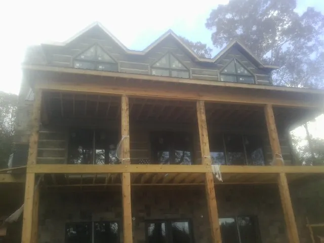 Dormers and porch framing on a large log home under construction — Roof Coating work by our crew in Essex